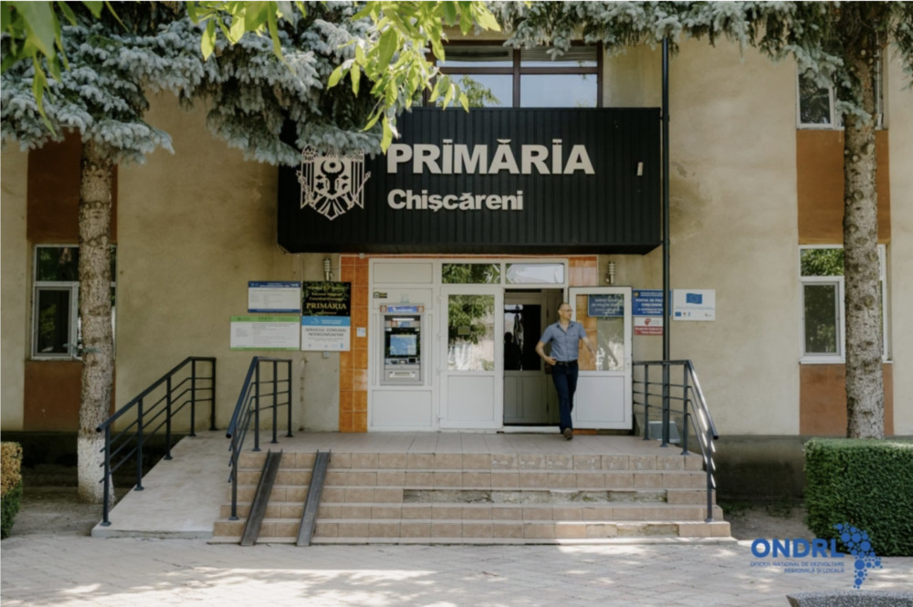 Town hall entrance (Primăria Chișcăreni) with a man stepping out of the doors.