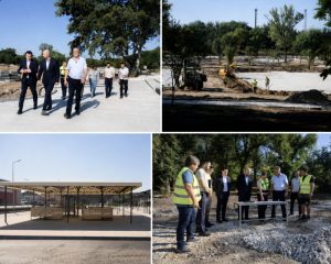 ungheni-proiecte-parc-piata Officials in suits inspect a sunny outdoor construction site, with workers and a dirt work area nearby.