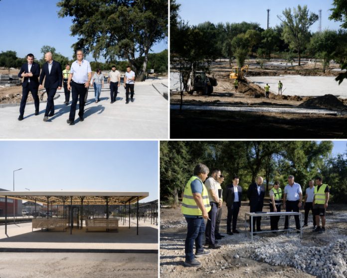 ungheni-proiecte-parc-piata Officials in suits inspect a sunny outdoor construction site, with workers and a dirt work area nearby.
